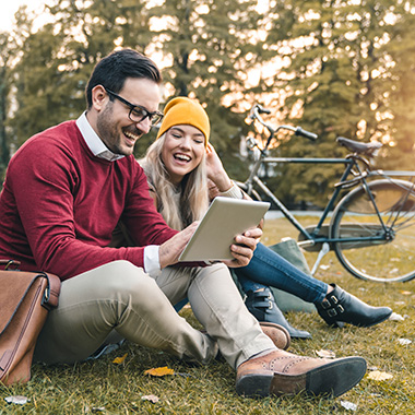 Young couple using tablet to shop while sitting in public park