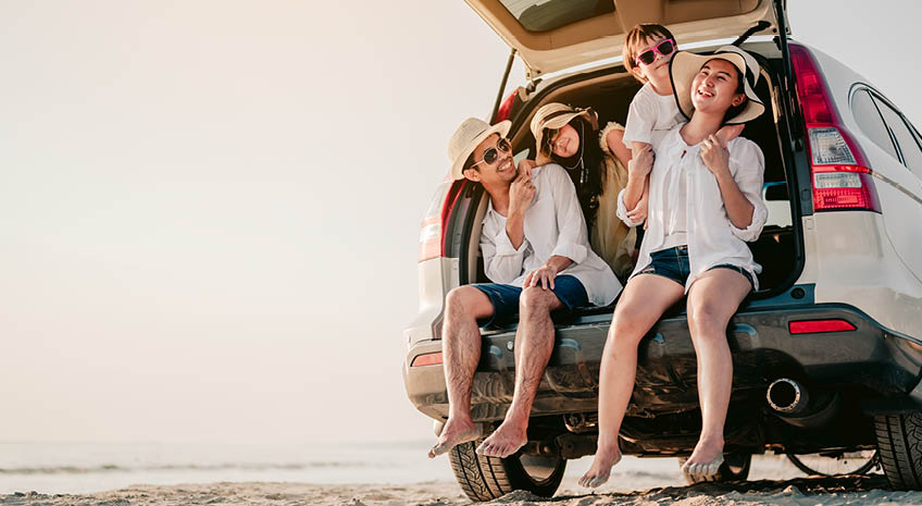 Happy asian family on a road trip in their car. Dad, mom and daughter are traveling by the sea. Summer ride by automobile.