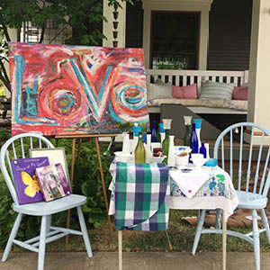 display table and chairs with artwork on easel at a yard sale