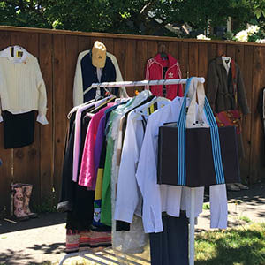 clothes for sale hnaging on a rack at a yard sale