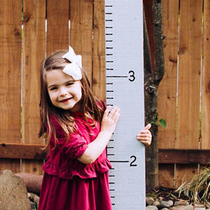 little girl next to a DIY fence board growth chart