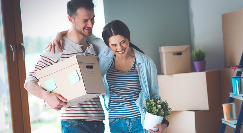 Happy young couple unpacking or packing boxes and moving into a new home