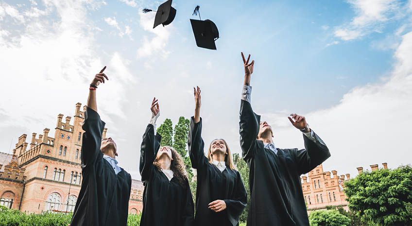 We've finally graduated!Graduates near university are throwing up hats in the air.
