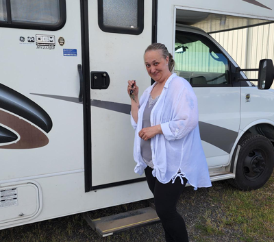 inroads member holding keys to her new RV, standing by RV door