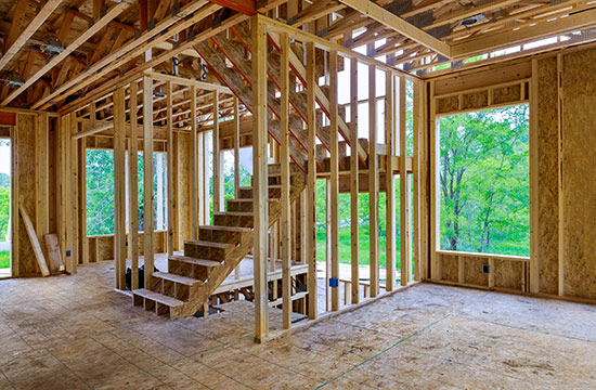 framed up construction walls of a home with no windows and trees in the distance