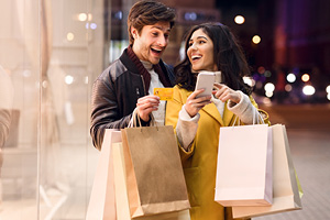 Consumerism concept. Happy couple checking cellphone outdoors