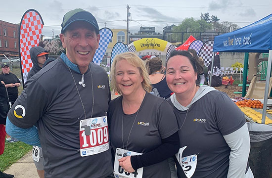 three InRoads employees wearing grey shirts with the InRoads logo and wearing race bibs