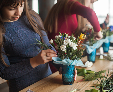 Women on the master-class on floristics. Young ladies making floral composition. Group of females with flowers indoor at the loft background. Decoration process