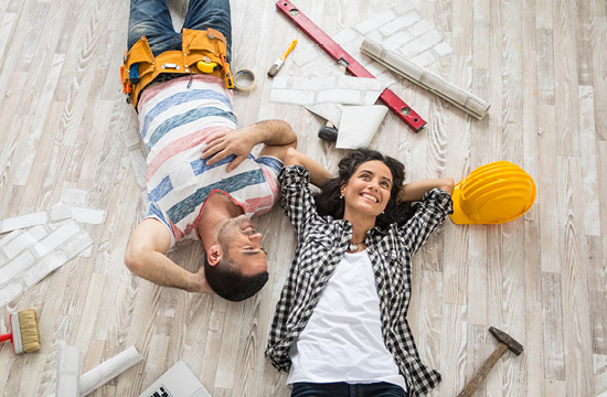 Couple renovating their home, resting and lying down on floor, high angle view.