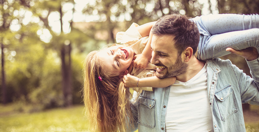 Happy smiling father and daughter spending summer day at park.