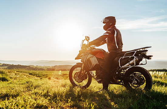person with helmet on a enduro motorcycle at sunset