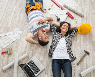 Couple renovating their home, resting and lying down on floor, high angle view.