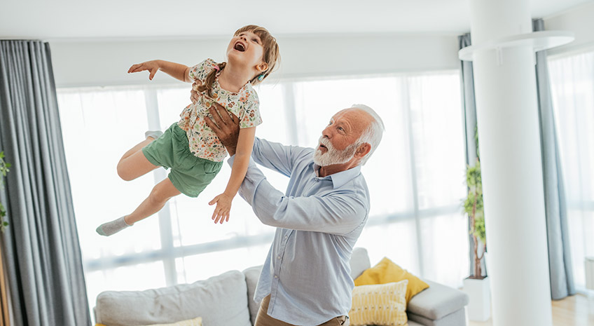 Image of senior man - grandfather and his granddaughter having fun at home