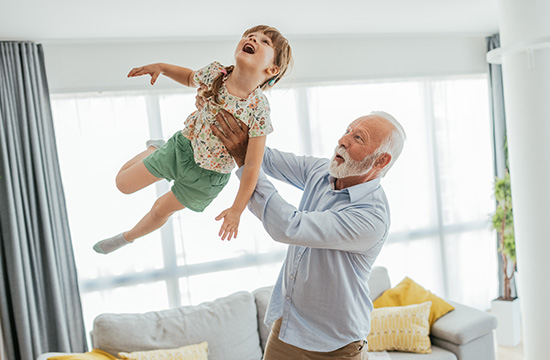 Image of senior man - grandfather and his granddaughter having fun at home