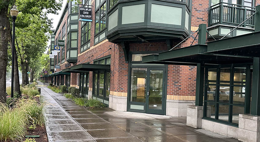 Facade of empty brick building with dark green trim and doors