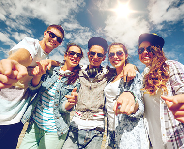 smiling teenagers in sunglasses hanging outside