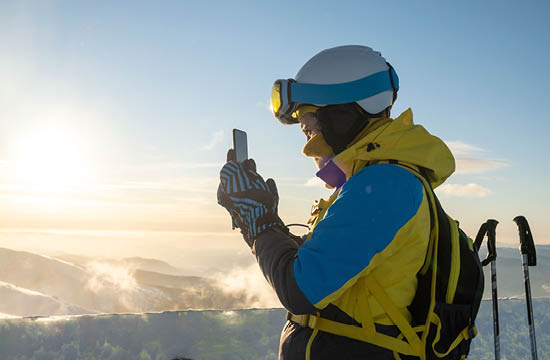 person on mountain skiing and checking phone