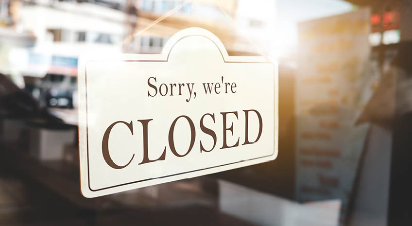 photo of a door sign that reads "sorry, we're closed"