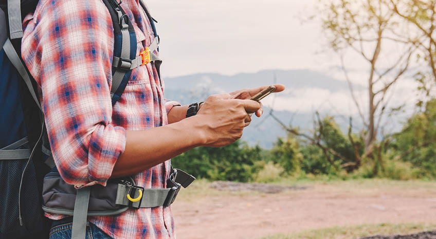 man on hike looking at phone