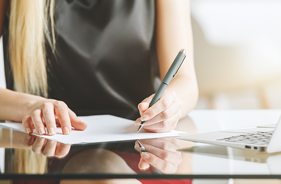 Close up of businesswoman hands doing paperwork at glass desk. Secretary concept