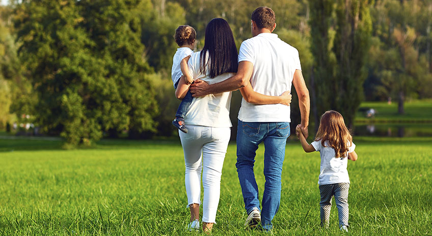 Rear view. Happy family with children walking in the park. Mother, father and children in nature.