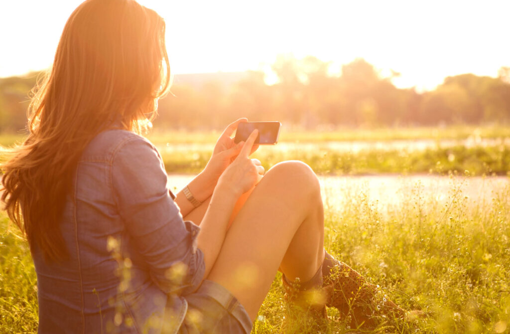 girl sitting in field holding phone