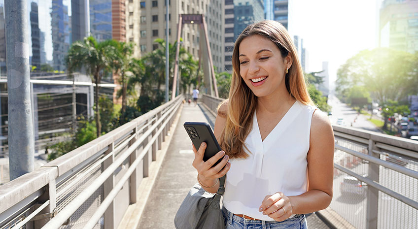 smiling woman outside looking at phone