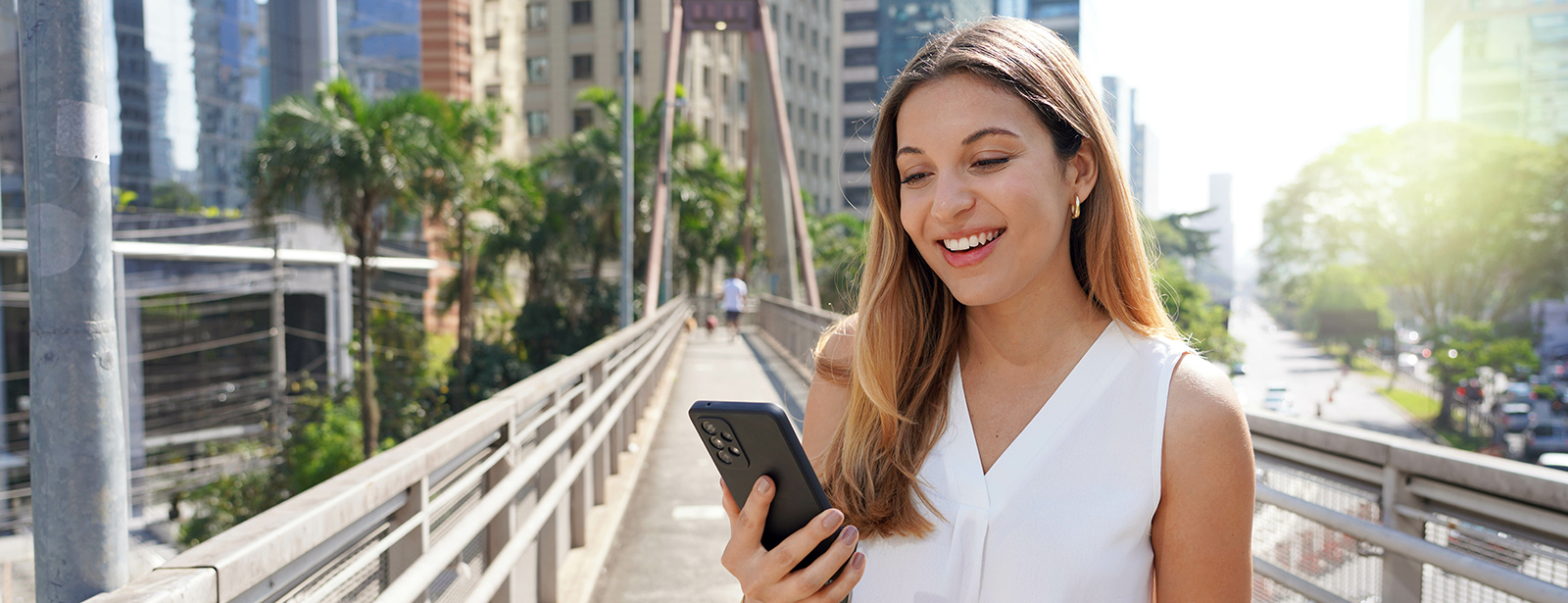 smiling woman outside looking at phone